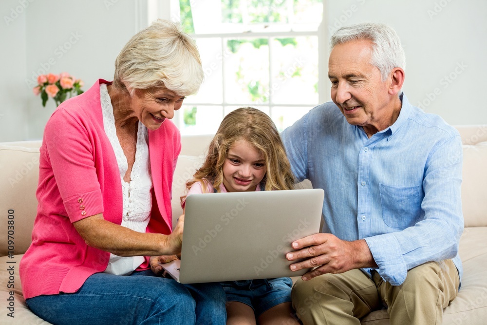 Smiling grandparents and girl using laptop 