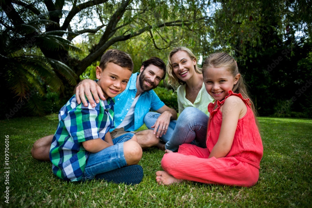 Happy family siting on grass in yard 