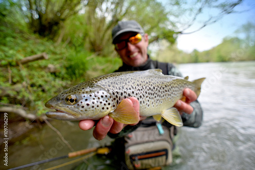 Fototapeta Naklejka Na Ścianę i Meble -  Happy fly-fisherman holding fario trout
