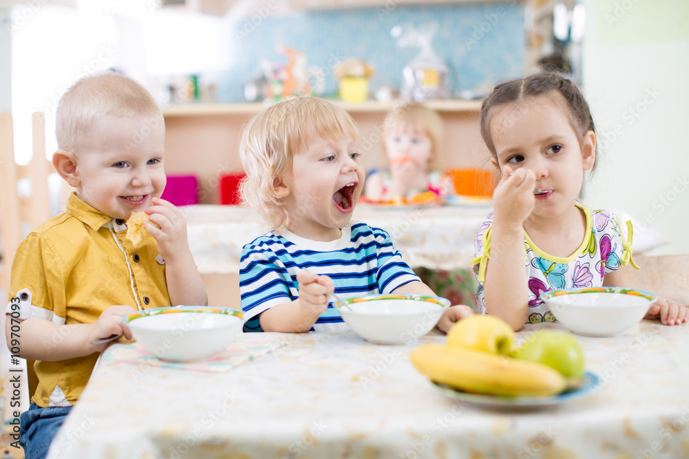 Funny little kid with open mouth eating in kindergarten group Funny little kid with open mouth eating in kindergarten group