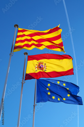 EU, Spain & Catalonia flags with plane trail in background
