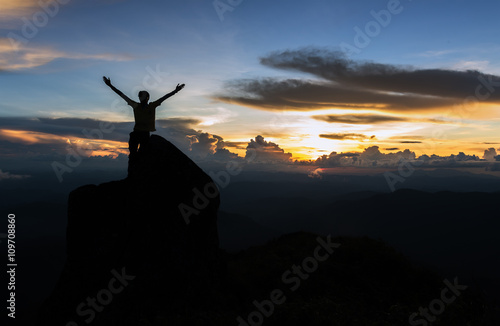 Silhouette man standing on giant rock and spreading hand on mountain