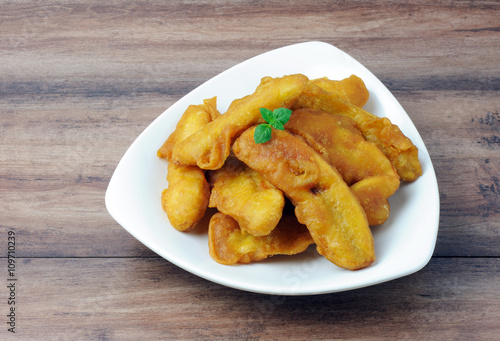 Fried banana in a plate on wooden table with copy space