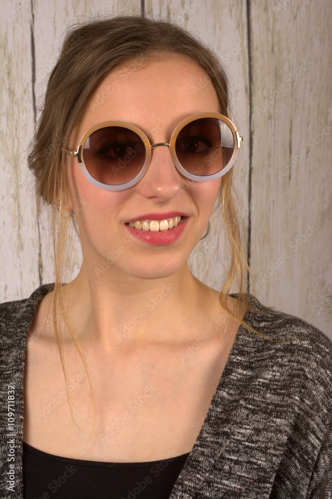 Junge Frau mit moderner Sonnenbrille vor rustikaler Holzwand - Portrait 