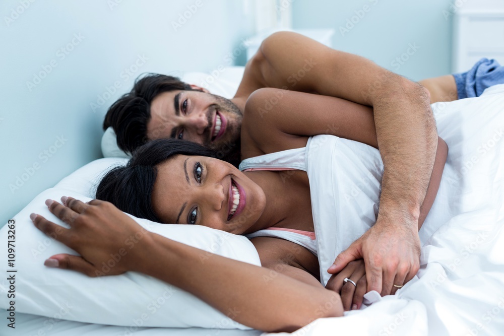 Young couple embracing while lying on bed Young couple embracing while lying on bed