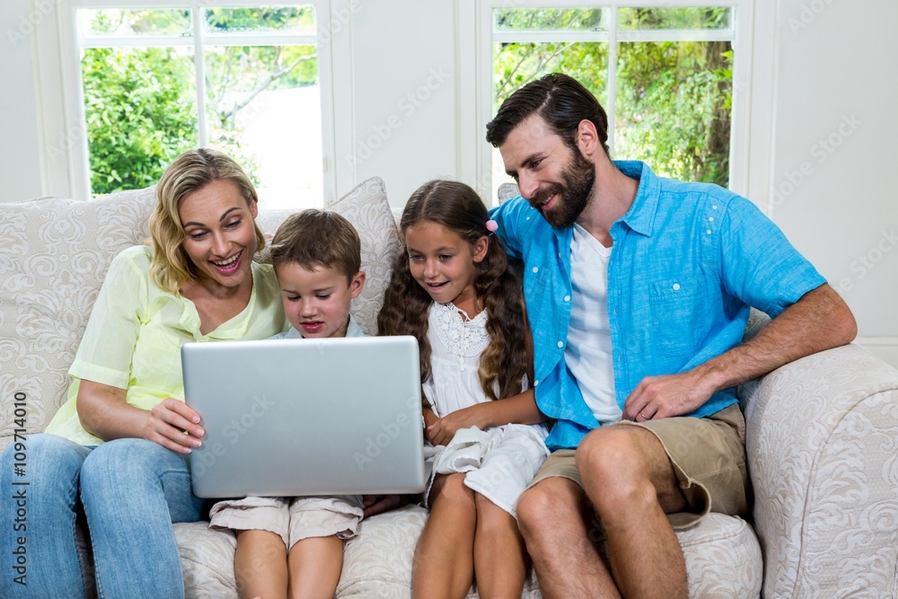 Smiling children with parents using laptop at home Smiling children with parents using laptop at home