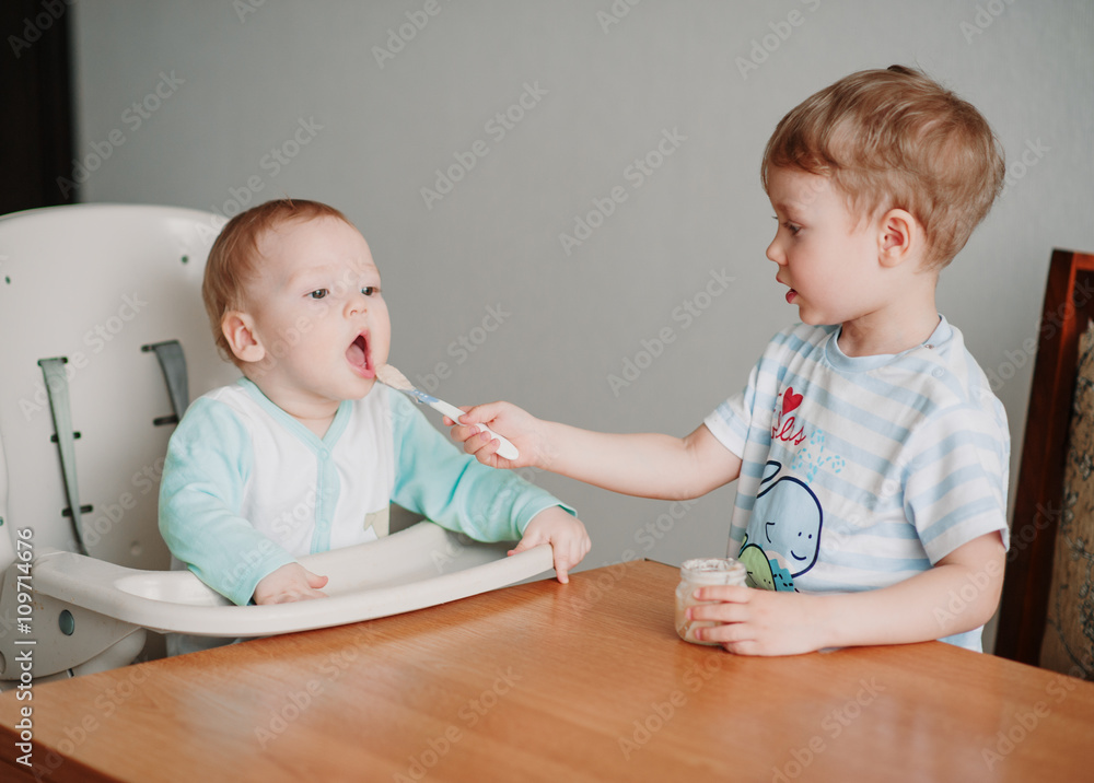 Brother feeding the younger child Brother feeding the younger child