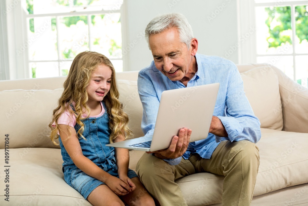 Smiling granddad and girl using laptop Smiling granddad and girl using laptop