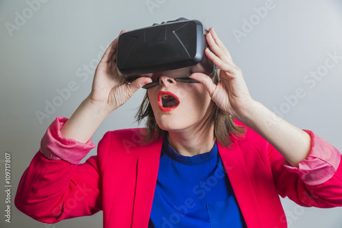 surprised and startled enthusiastic young beautiful girl l getting experience using VR-headset glasses of virtual reality gesticulating hands