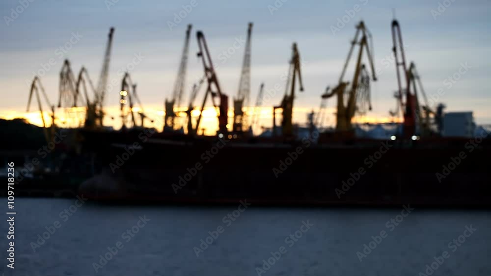Silhouettes of cranes in the port on the river Silhouettes of cranes in the port on the river