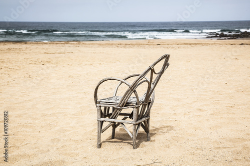 silla de caña en una playa desierta con olas y cielo al fondo © tingitania