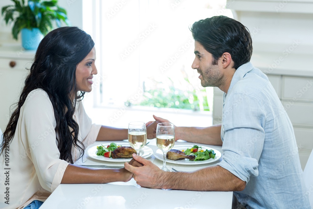 Young couple talking while having meal in kitchen