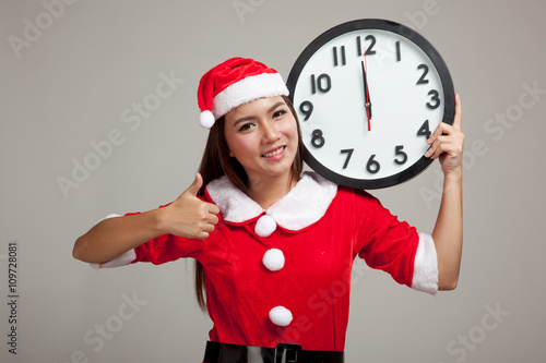 Asian Christmas girl in Santa Claus clothes and clock at midnigh photo