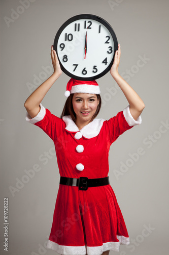 Asian Christmas girl in Santa Claus clothes and clock at midnigh photo