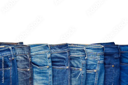 Row of fashion different jeans isolated on white background.
