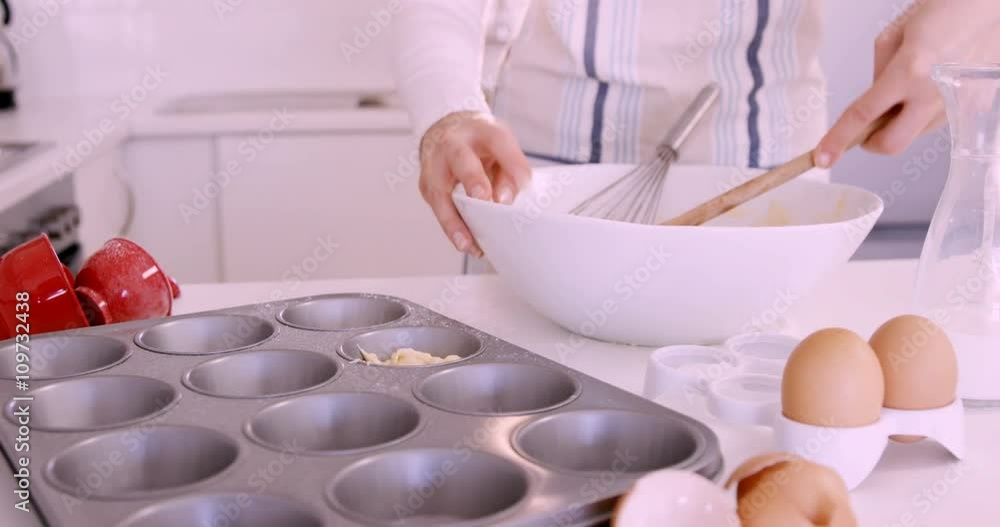 Woman putting dough in muffin mold Woman putting dough in muffin mold