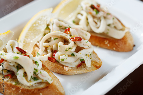 appetizer with spicy squids and lemon on toast