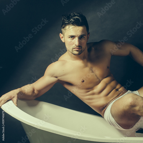 Muscular man on bathtub