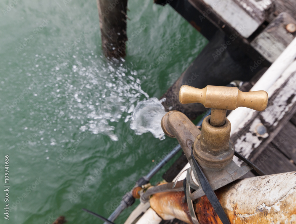 A leaking old rusty tap at a fishing cleaning station on a fishing jetty A leaking old rusty tap at a fishing cleaning station on a fishing jetty
