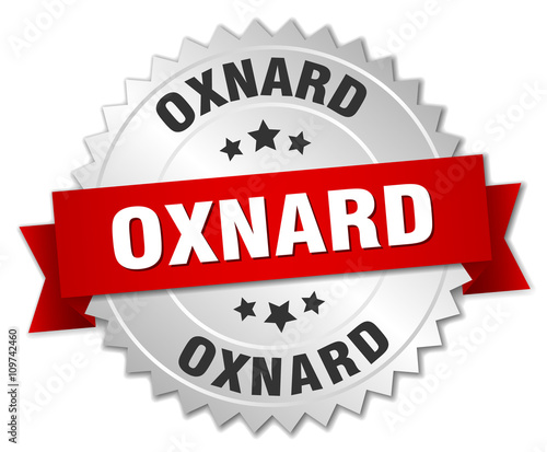 Oxnard round silver badge with red ribbon