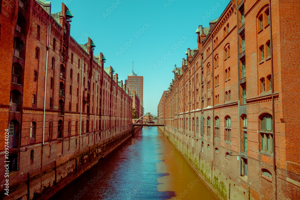 Large river canal with bricks buildings on the sides, sun and shadow, color mix