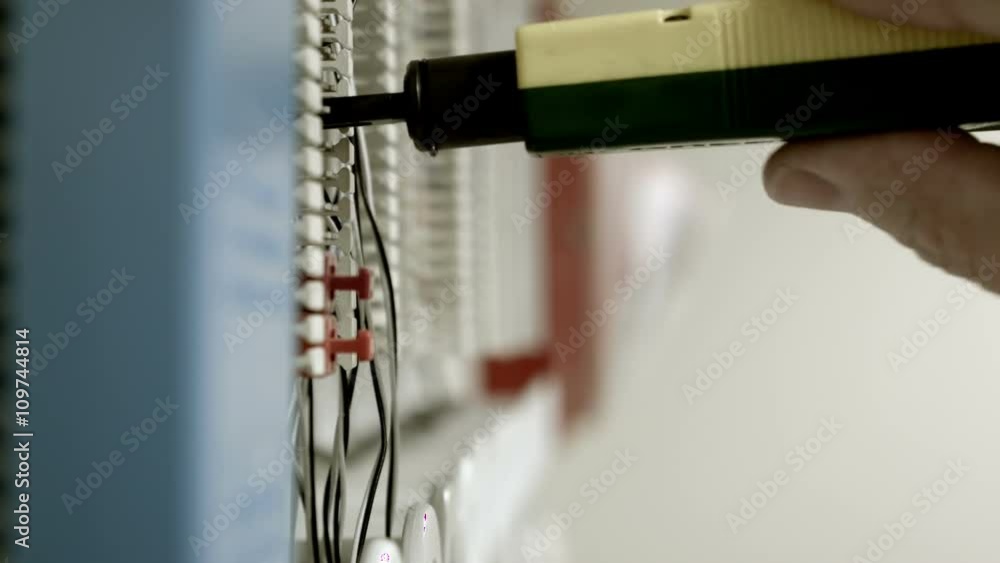 A technician using a punch down tool to check the connections on a