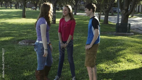 A teenage boy teases his friends by not letting them see a message he just got on his smart phone.