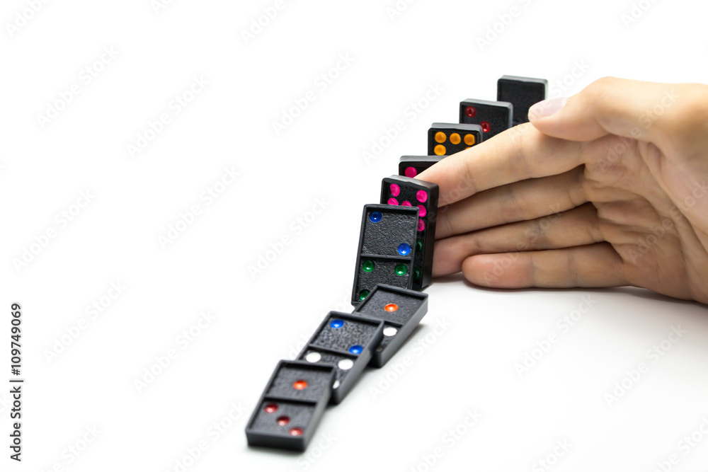 Businessman hand stopping domino effect on isolated white background Businessman hand stopping domino effect on isolated white background