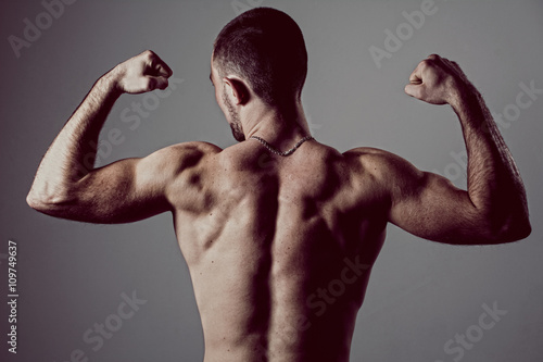 Portrait of a handsome muscular young man from the back. Shot in a studio. Toned image © kanzefar