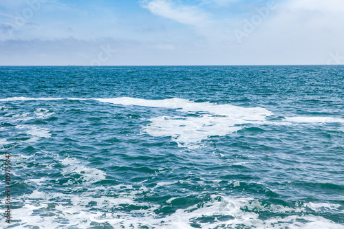 Blue sea with waves and sky with clouds