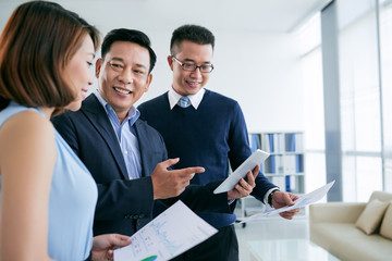 Group of Asian people discussing charts