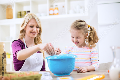 Mother putting flour in to the mixture