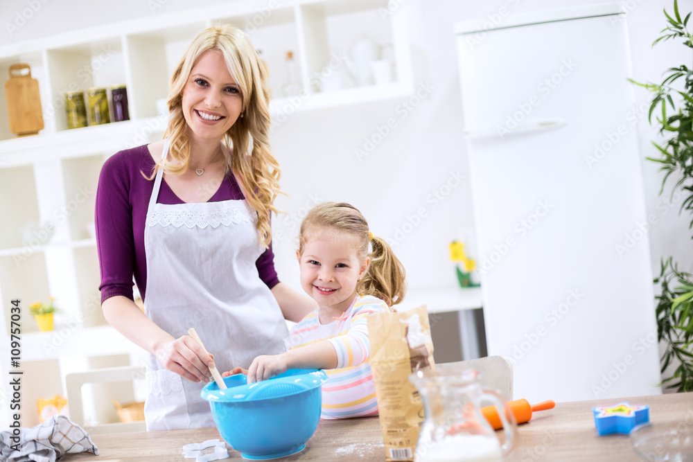 Smiling child and mother cooking together Smiling child and mother cooking together