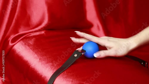 Fetish bdsm gag  in female hand. sex toys. red sheets