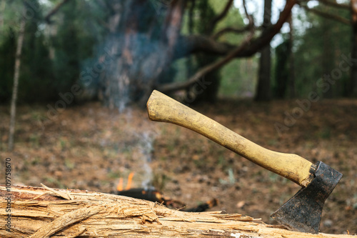 Iron ax near the fire near the camp. Journey into the wild concept. 