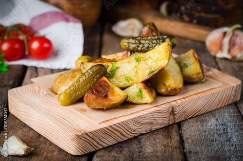 Roasted potatoes with garlic and fennel on wood plate, wooden background. Selective focus