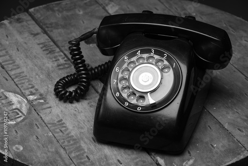 Old black phone with dust and scratches, isolated on wooden retro floor