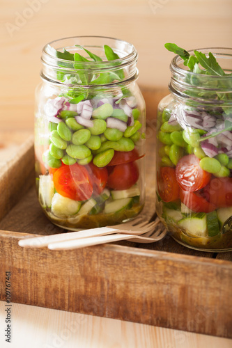 healthy vegetable salad in mason jar: tomato, cucumber, soybean,