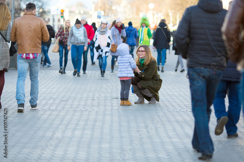 Mother and Daughter walking on City Street among Crowd