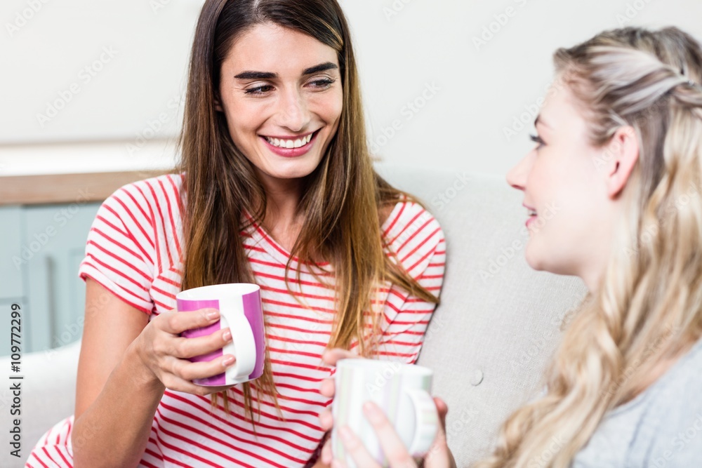 Beautiful female friends smiling while drinking coffee Beautiful female friends smiling while drinking coffee