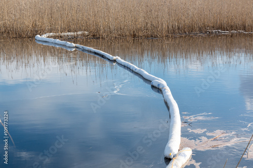 Floating oil containment boom at a calm lake after an oil spill