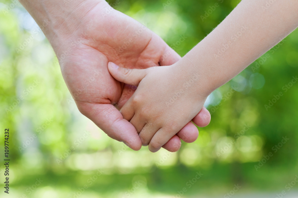 Father holds hand of the child against beautiful bokeh background in sunny day, happy family concept, shallow dof Father holds hand of the child against beautiful bokeh background in sunny day, happy family concept, shallow dof