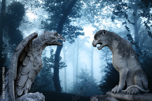 Fotografija Ancient eagle and lion statues in misty forest