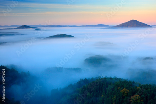Cold misty foggy morning in a fall valley of Bohemian Switzerland park. Hills with fog, landscape of Czech Republic