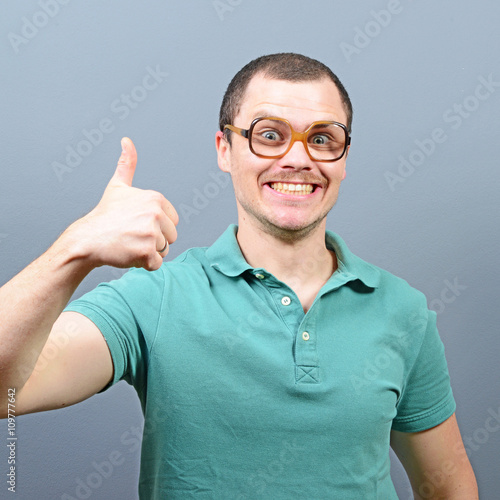 Portrait of a man showing thumb up sign against gray background