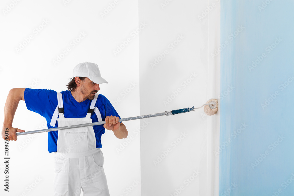 Painter painting a wall with paint roller Painter painting a wall with paint roller