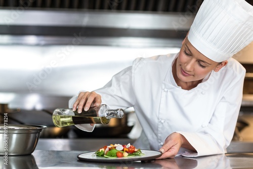 Female chef pouring oil on food in plate