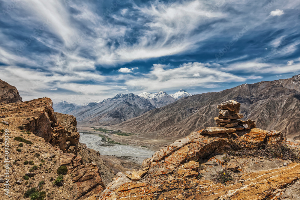 View of valley in Himalayas with stone cairn on cliff