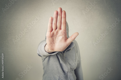 Hooded person showing stop gesture