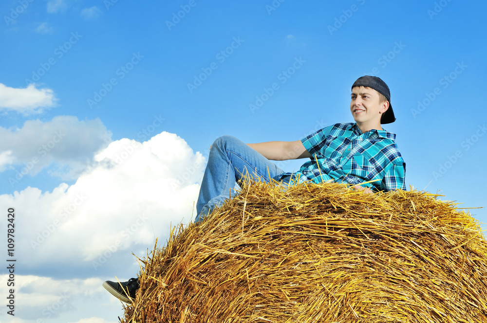 man on a stack of straw against a field man on a stack of straw against a field